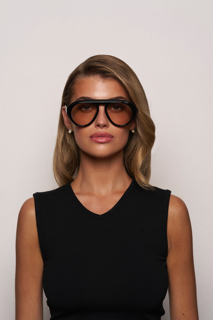 Woman wearing large sunglasses against a plain background
