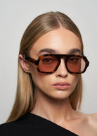 Person wearing a pair of sunglasses with a plain background